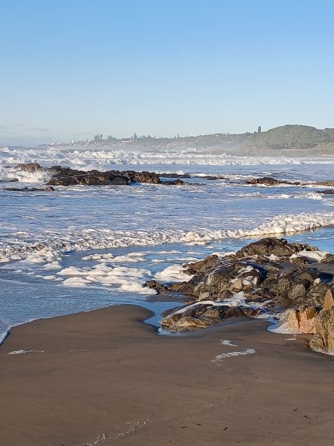 Wide Leisure Bay shoreline, surf and forested headland
